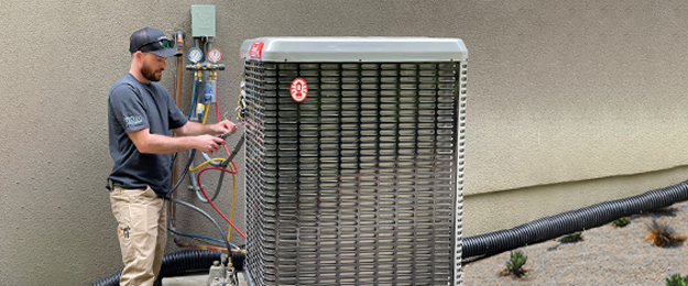 A technician connects cables and wiring to an HVAC unit